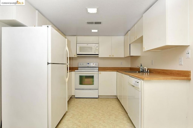 kitchen featuring white appliances, white cabinetry, and sink