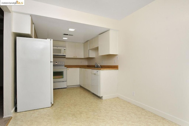 kitchen with cream cabinets, sink, and white appliances