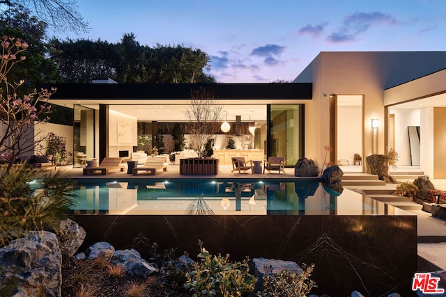 pool at dusk with a patio and outdoor lounge area