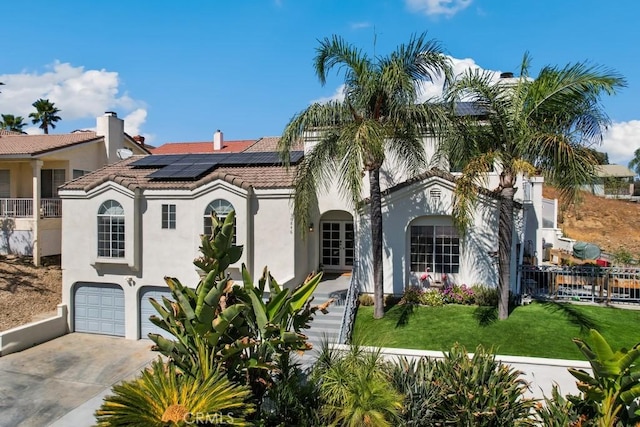 mediterranean / spanish house featuring a front yard, solar panels, and a garage