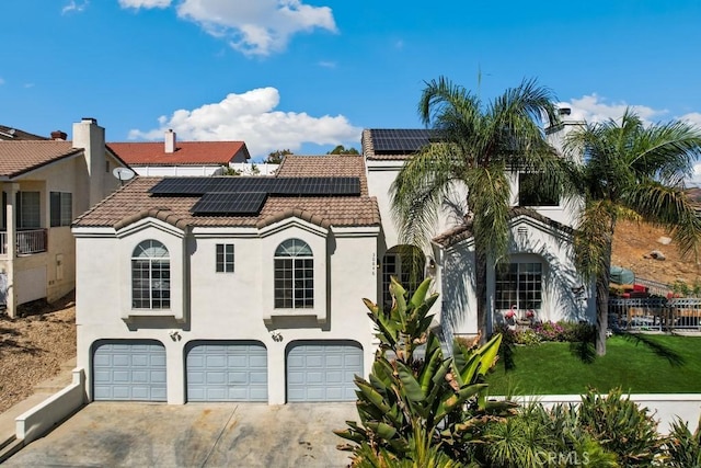 mediterranean / spanish-style home featuring solar panels, a garage, and a front yard