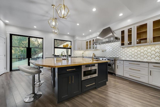 kitchen featuring white cabinetry, wall chimney range hood, and hardwood / wood-style flooring