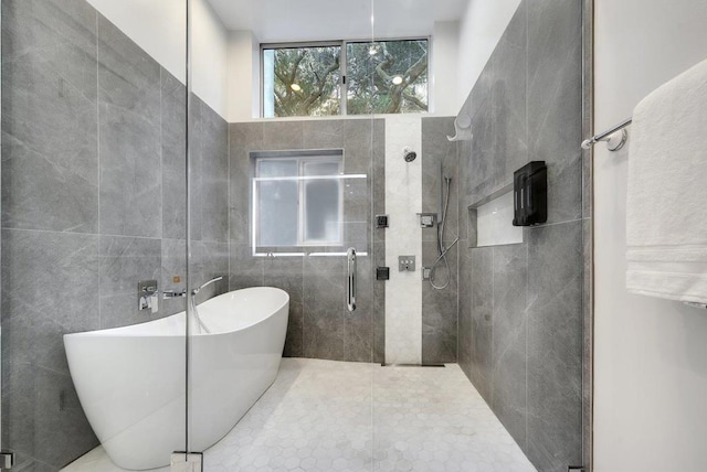 bathroom featuring tile patterned flooring, tile walls, and independent shower and bath