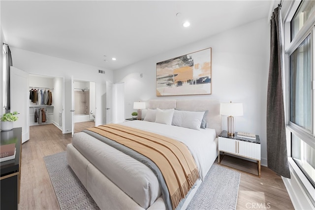 bedroom with a spacious closet, a closet, light hardwood / wood-style floors, and ensuite bathroom