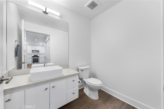 bathroom with hardwood / wood-style flooring, vanity, and toilet