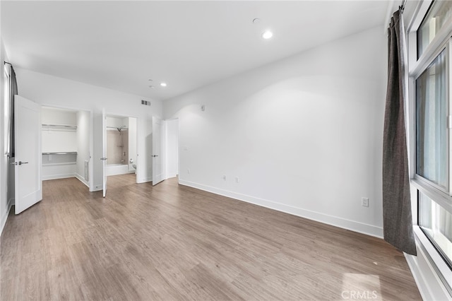 unfurnished bedroom featuring light wood-type flooring, a walk in closet, and a closet