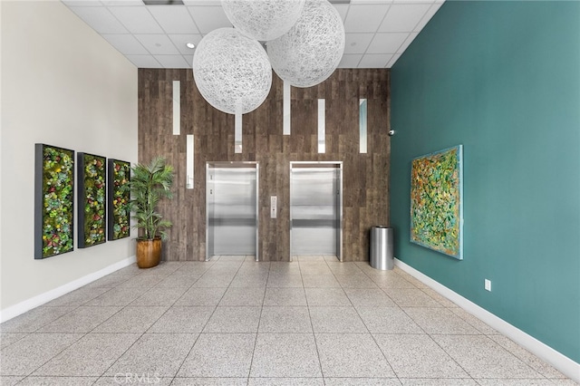 unfurnished living room featuring a high ceiling, wooden walls, and elevator