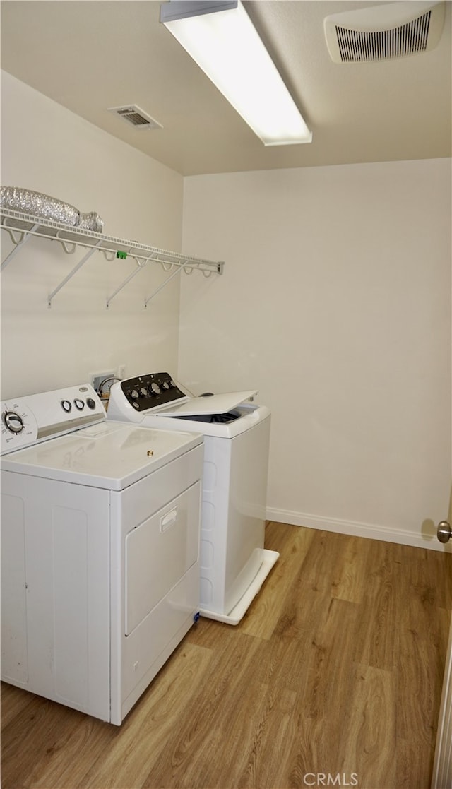 laundry area featuring washer and clothes dryer and light hardwood / wood-style floors