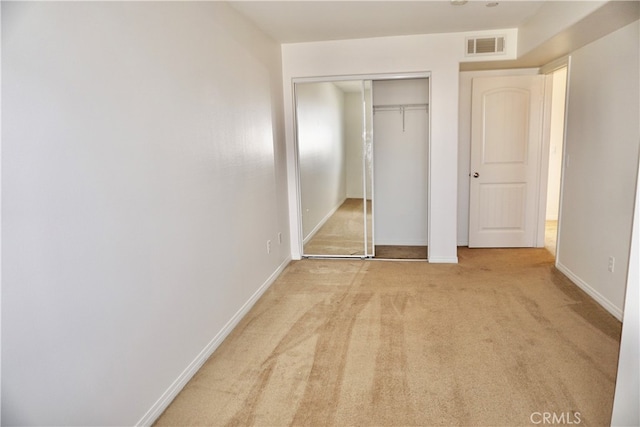 unfurnished bedroom with a closet and light colored carpet