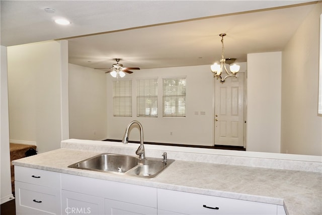 kitchen featuring ceiling fan with notable chandelier, white cabinets, hanging light fixtures, and sink