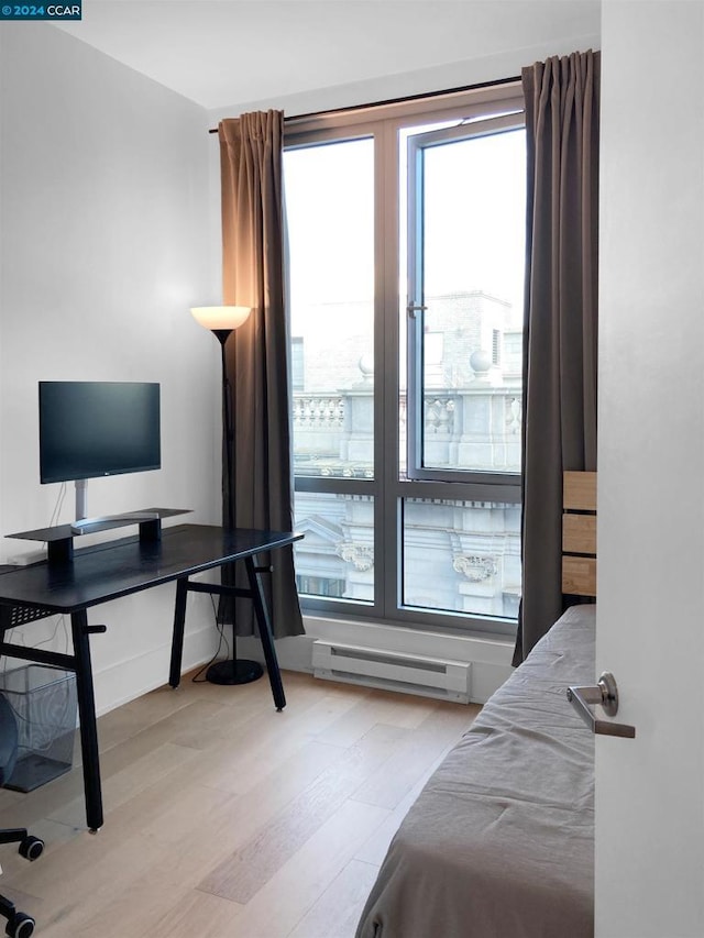 bedroom featuring light wood-type flooring and baseboard heating