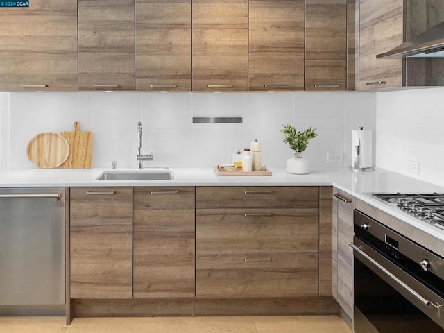 kitchen with wall chimney range hood, decorative backsplash, stainless steel appliances, and sink