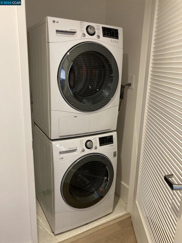 laundry area featuring stacked washing maching and dryer and light hardwood / wood-style flooring