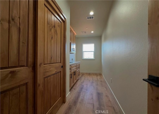 corridor with recessed lighting, visible vents, baseboards, and light wood finished floors