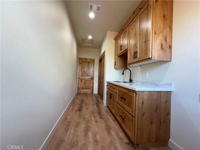 interior space featuring visible vents, a sink, recessed lighting, light wood-style floors, and baseboards