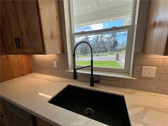 kitchen featuring light stone countertops, backsplash, and a sink