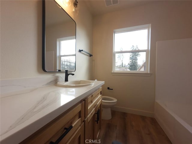 full bath with visible vents, baseboards, toilet, wood finished floors, and vanity