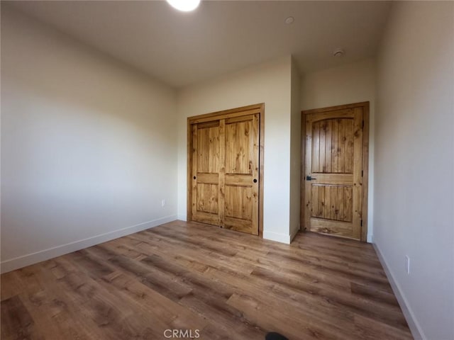 unfurnished bedroom featuring wood finished floors and baseboards