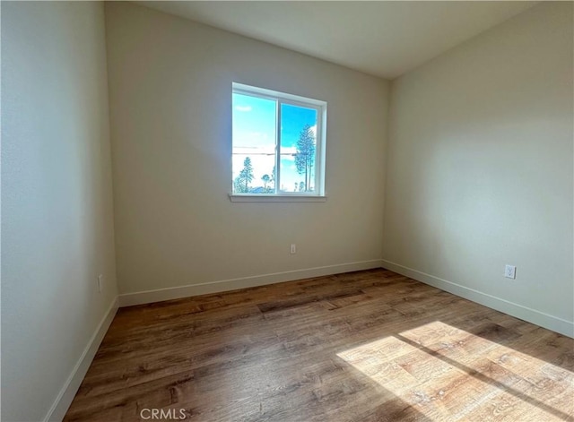 spare room featuring baseboards and wood finished floors