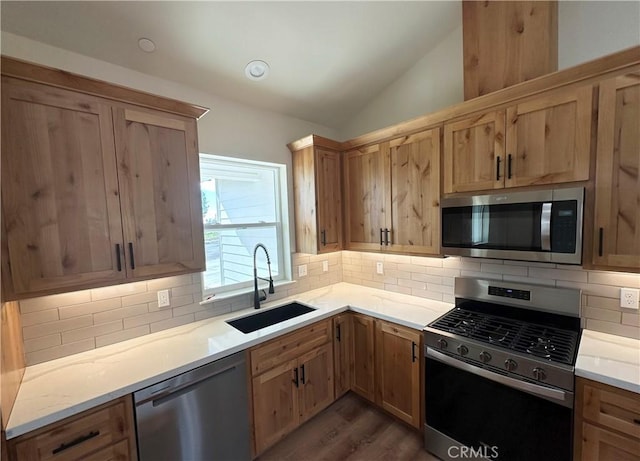 kitchen with a sink, vaulted ceiling, backsplash, and stainless steel appliances