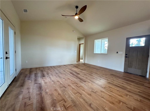 interior space featuring a ceiling fan, wood finished floors, visible vents, baseboards, and vaulted ceiling