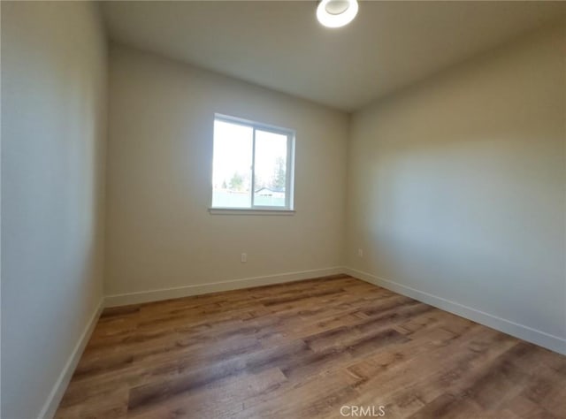 spare room featuring baseboards and wood finished floors