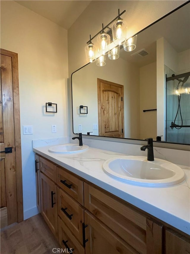 full bath with double vanity, wood finished floors, a stall shower, and a sink