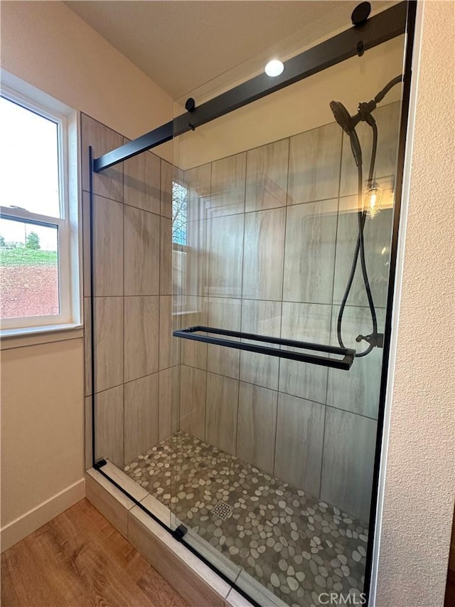 bathroom with baseboards, wood finished floors, and a stall shower