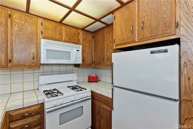 kitchen featuring tile counters, white appliances, and tasteful backsplash