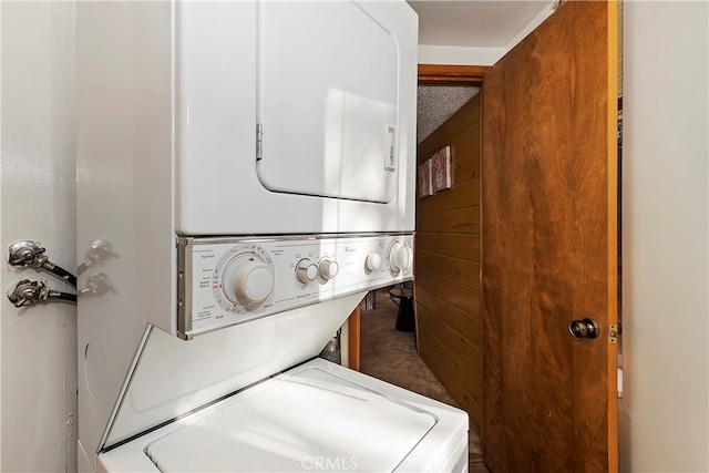 clothes washing area featuring stacked washer / dryer and a textured ceiling