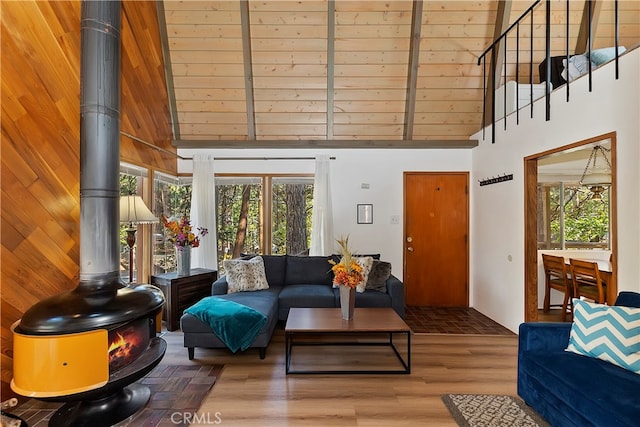 living room featuring a wood stove, wood walls, a high ceiling, and hardwood / wood-style floors