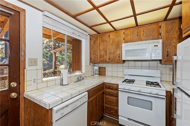 kitchen featuring white appliances, tile countertops, sink, and backsplash