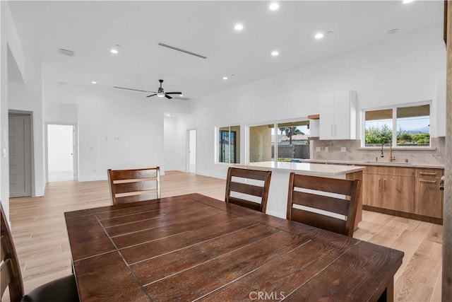 dining area with ceiling fan, sink, and light hardwood / wood-style flooring