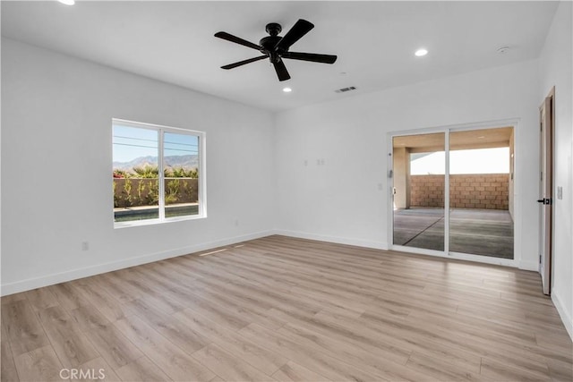 empty room with ceiling fan and light hardwood / wood-style flooring