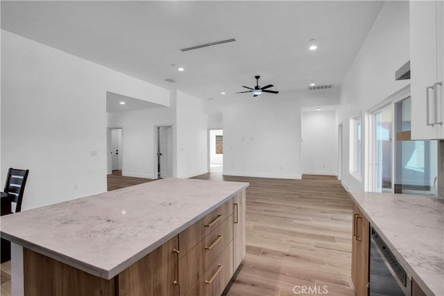 kitchen with dishwasher, light hardwood / wood-style flooring, ceiling fan, light stone countertops, and a kitchen island