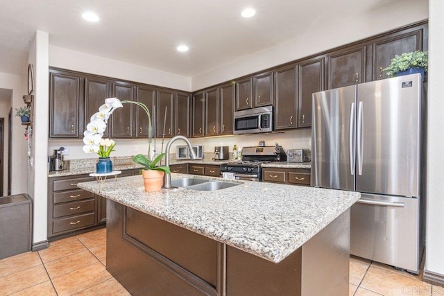 kitchen with a center island with sink, sink, light tile patterned floors, dark brown cabinets, and stainless steel appliances