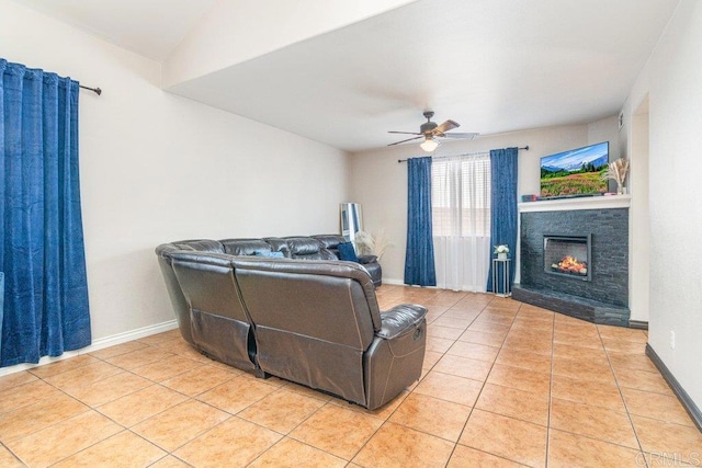 tiled living room featuring a stone fireplace and ceiling fan