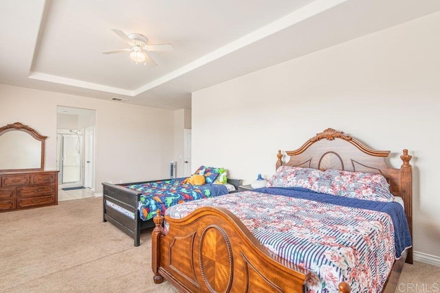 carpeted bedroom with ceiling fan and a tray ceiling