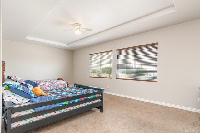 bedroom with carpet, ceiling fan, and a tray ceiling