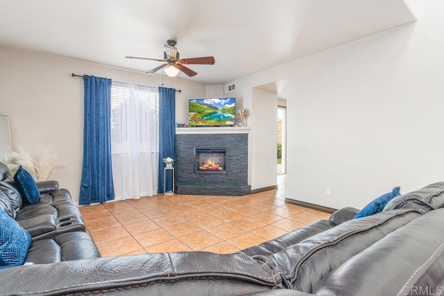 living room with a fireplace, light tile patterned floors, and ceiling fan