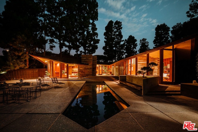 pool at dusk with a patio area