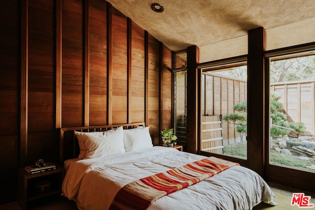 bedroom featuring wooden walls, lofted ceiling, and access to exterior