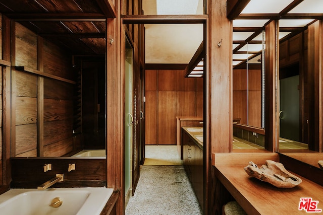 bathroom with wood walls, a bath, and vanity