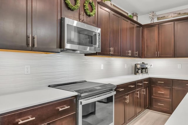 kitchen with decorative backsplash, dark brown cabinets, stainless steel appliances, and light hardwood / wood-style flooring