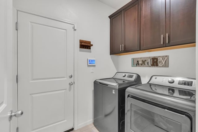 laundry room with washer and dryer, cabinets, and light tile patterned floors