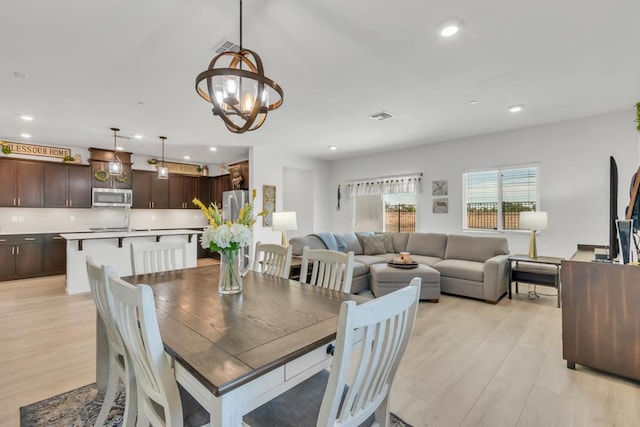 dining area with light wood-type flooring and an inviting chandelier