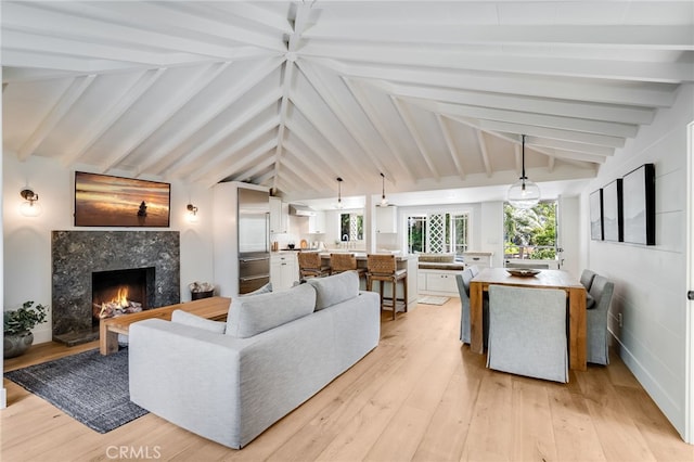 living room with light hardwood / wood-style flooring, lofted ceiling with beams, and a fireplace