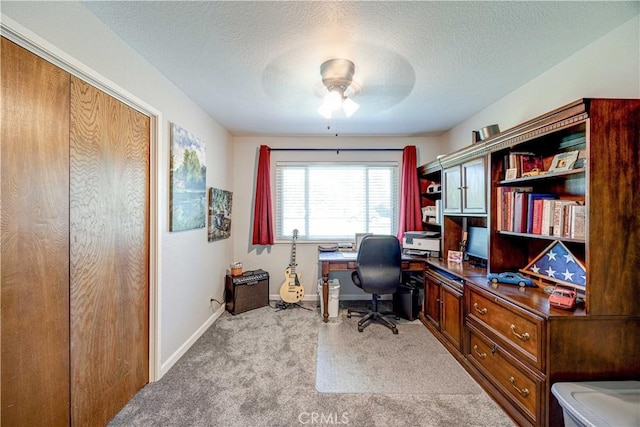 carpeted home office featuring ceiling fan and a textured ceiling