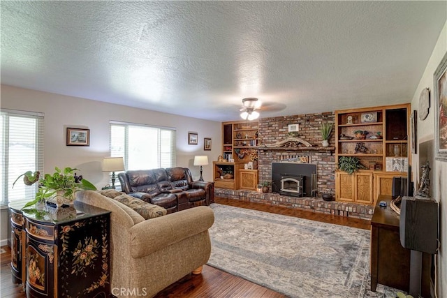 living room with hardwood / wood-style flooring, built in features, a textured ceiling, and a wood stove