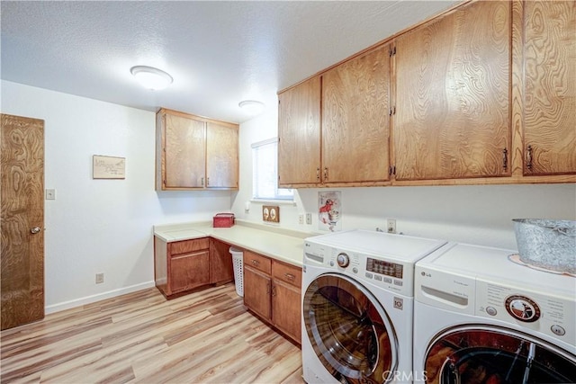 clothes washing area with cabinets, light wood-type flooring, a textured ceiling, and independent washer and dryer